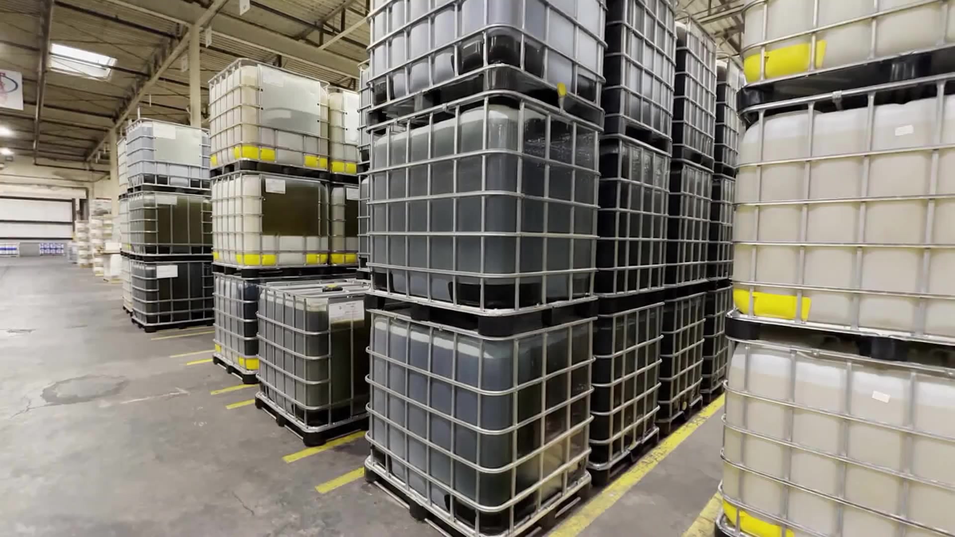 Tracking view through a clean warehouse aisle lined with industrial totes